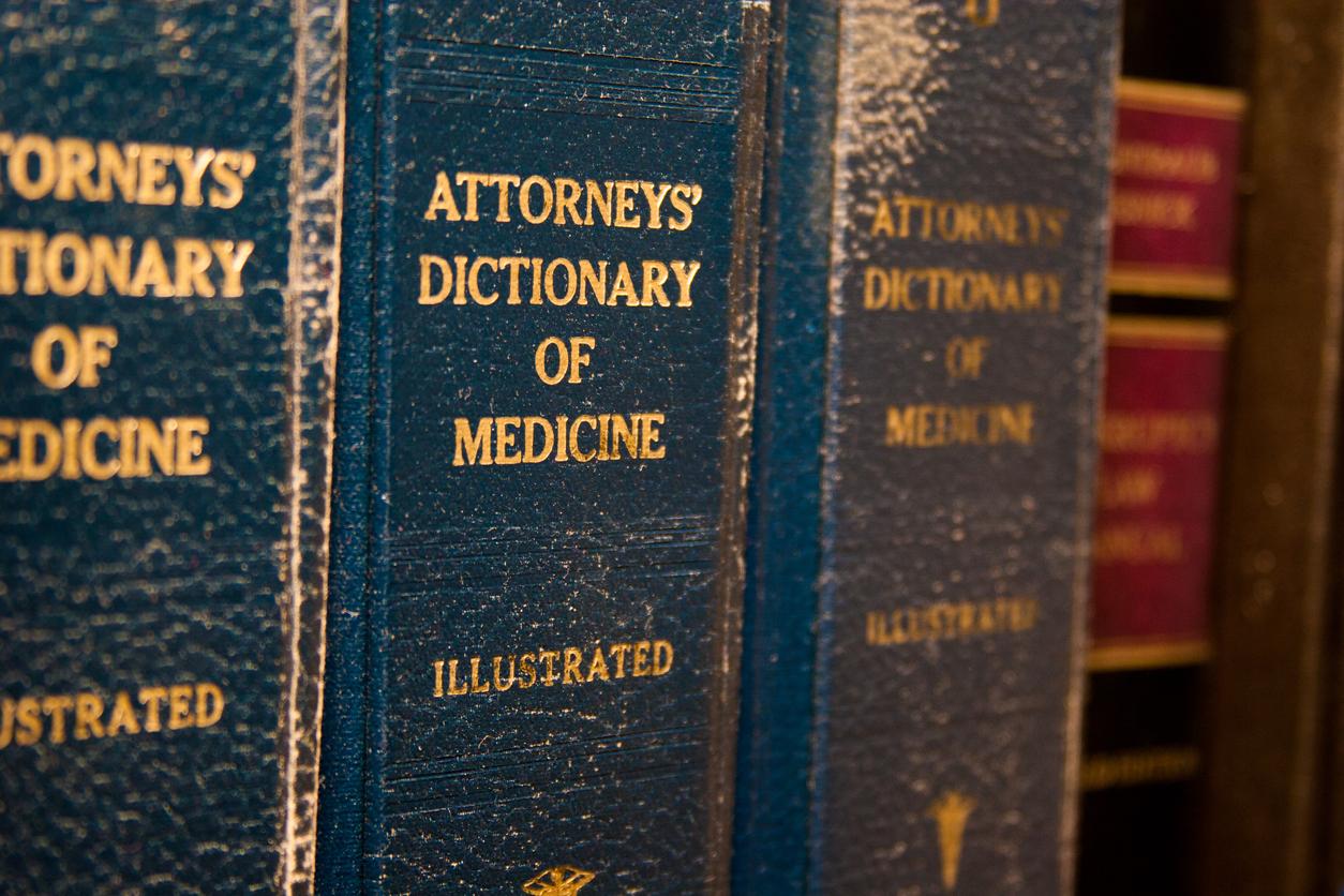Series of 3 blue books on a shelf with titles reading, 'Attorneys` Dictionary of Medicine'