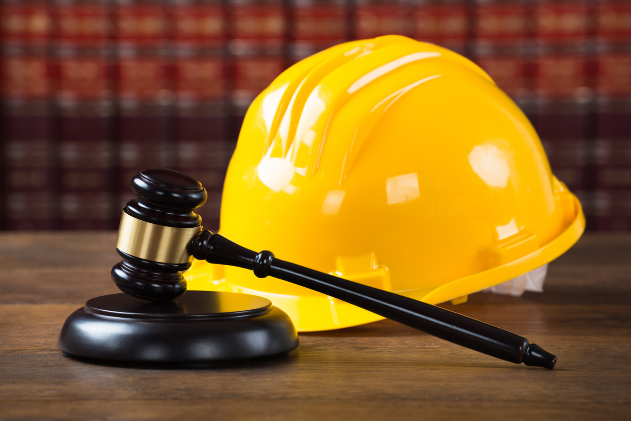 Closeup of wooden mallet and yellow hardhat on table in courtroom